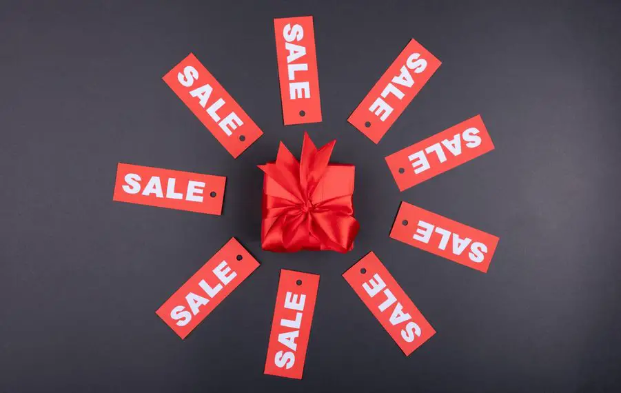 Sales signs in a circle around a red bow and box
